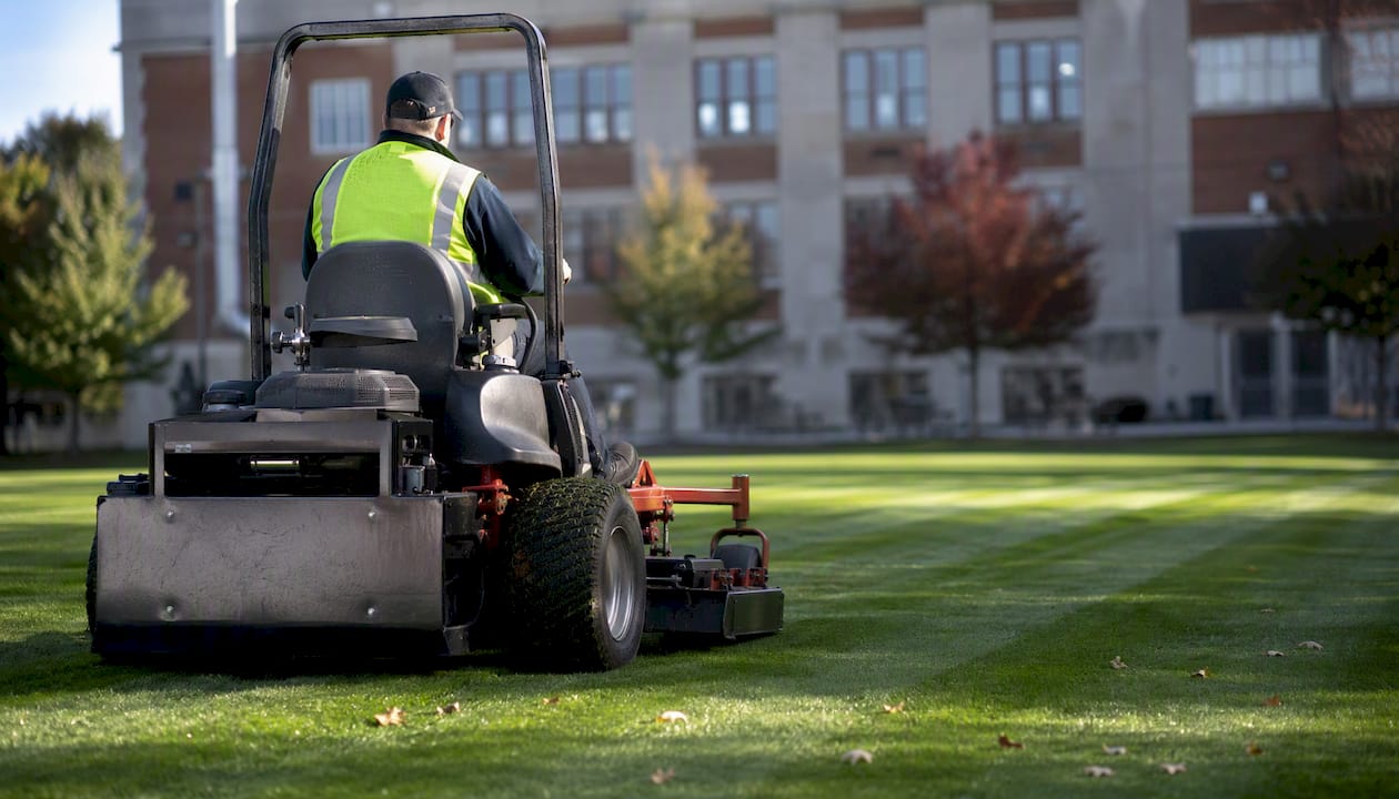 Maintenance worker mowing school lawn