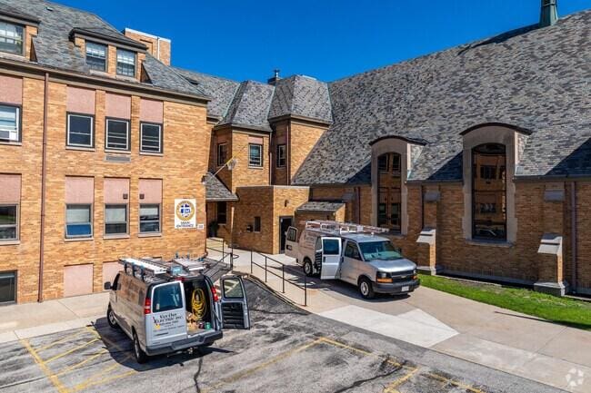 Maintenance and service vans parked outside a brick university campus building