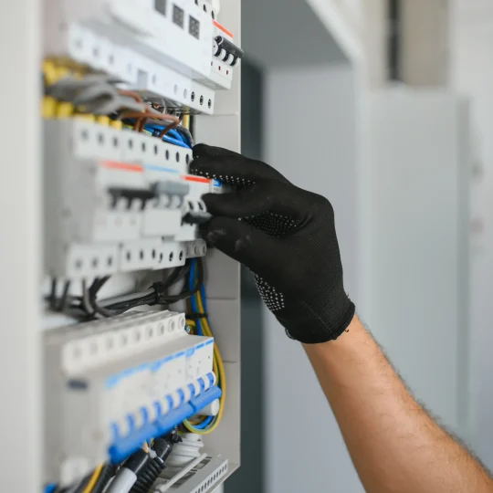 Electrician wearing a work glove resetting a circuit breaker in a customer's distribution panel